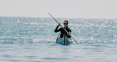 mujer mar kayac. contento sonriente mujer en kayac en océano, remar con de madera remo. calma mar agua y horizonte en antecedentes. activo estilo de vida a mar. verano vacaciones. foto