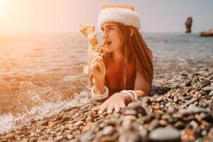 Woman travel sea. Happy tourist enjoy taking picture on the beach for memories. Woman traveler in Santa hat looks at camera on the sea bay, sharing travel adventure journey photo