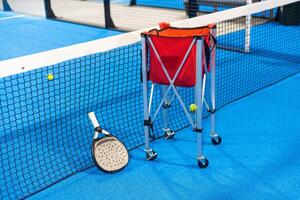 Paddle tennis. Paddel racket and ball in front of an outdoor court photo