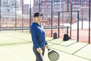 uno mujer con raqueta y pelota detrás el red en paleta tenis Corte Listo para formación foto