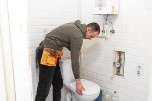 Plumber repairing a toilet cistern photo