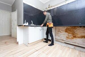 Older man disassembling apartment kitchen out of service photo