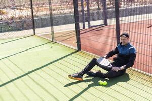 retrato de positivo joven hombre con raqueta y padel pelota en tenis Corte foto