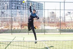 Young padel player trains by catching high balls photo