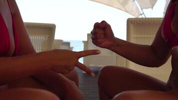 Rock paper scissors being played by two young woman. Close up view female hands playing stone, scissors and paper on sea background, funny carefree game. Friendship, dealing with conflict, having fun. video