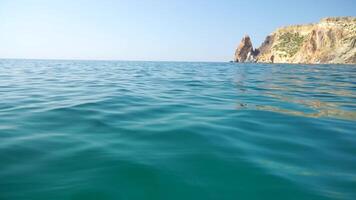 Sea water surface. Camera flies over the calm azure sea with volcanic rocky shores on background. Nobody. Holiday recreation concept. Abstract nautical summer ocean nature. Slow motion. Close up video