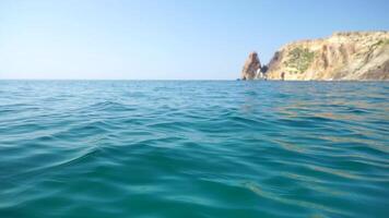 Sea water surface. Camera flies over the calm azure sea with volcanic rocky shores on background. Nobody. Holiday recreation concept. Abstract nautical summer ocean nature. Slow motion. Close up video