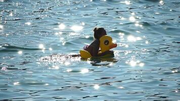 Summer Vacation Woman floats on an inflatable donut mattress, a water toy swim ring. Positive happy woman relaxing and enjoying family summer travel holidays vacation on the sea. Slow motion video