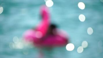 astratto sfocato estate vacanza donna galleggia su gonfiabile rosa fenicottero, acqua giocattolo nuotare squillo. positivo contento donna rilassante e godendo famiglia estate viaggio vacanze vacanza su mare. lento movimento video