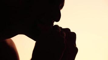 Silhouette of a man enjoying eating of a hamburger. Side view portrait of a person savoring a delicious, satisfying burger with great appetite. Fast food indulgence. video