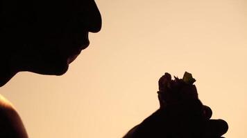 Silhouette of a man enjoying eating of a hamburger. Side view portrait of a person savoring a delicious, satisfying burger with great appetite. Fast food indulgence. video