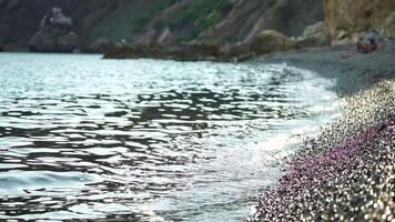 astratto mare estate oceano tramonto natura sfondo. piccolo onde su d'oro acqua superficie nel movimento sfocatura con d'oro bokeh luci a partire dal sole. vacanza, vacanza e ricreativo concetto. nessuno lento movimento video