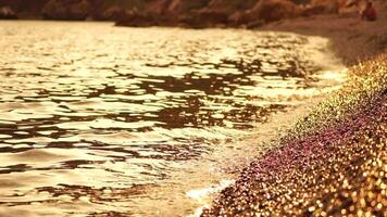 Abstract sea summer ocean sunset nature background. Small waves on golden water surface in motion blur with golden bokeh lights from sun. Holiday, vacation and recreational concept. Nobody Slow motion video