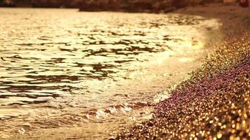 Abstract sea summer ocean sunset nature background. Small waves on golden water surface in motion blur with golden bokeh lights from sun. Holiday, vacation and recreational concept. Nobody Slow motion video