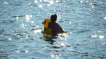 verano vacaciones mujer flotadores en un inflable rosquilla colchón, un agua juguete nadar anillo. positivo contento mujer relajante y disfrutando familia verano viaje Días festivos vacaciones en el mar. lento movimiento video