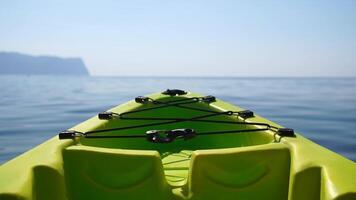 Sea water surface. Camera flies over the calm azure sea with green kayak boat on foreground. Nobody. Holiday recreation concept. Abstract nautical summer ocean nature. Slow motion. Close up video