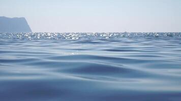 mare acqua superficie. telecamera mosche al di sopra di il calma azzurro mare con vulcanico roccioso sponde su sfondo. nessuno. vacanza ricreazione concetto. astratto nautico estate oceano natura. lento movimento. vicino su video