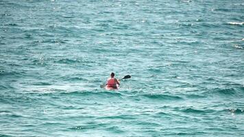 hombre kayac mar. fuerte atlético hombre aprende a paleta kayac en abierto mar Oceano en soleado día. verano fiesta vacaciones y viaje concepto. aéreo vista. lento movimiento video