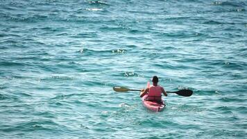 homme kayak mer. fort athlétique homme apprend à pagayer kayak dans ouvert mer océan sur ensoleillé journée. été vacances vacances et Voyage concept. aérien voir. lent mouvement video