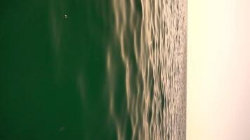 Vertical aerial view on sea water surface, camera flies over clear sea water. Sun glare. Abstract nautical summer ocean nature. Holiday, vacation and travel concept. Nobody. Weather and climate change video
