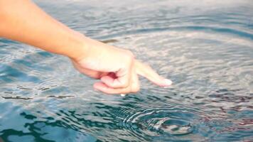 Woman hand sea. Close-up Happy Woman gently caresses water surface at sunset in a warm, golden evening by the sea or lake. Slow-motion Concept of happiness, boat life and holidays in exotic places video