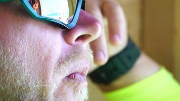 hombre comiendo hielo crema. de cerca retrato de joven hipster hombre en gafas de sol comiendo hielo crema en verano caliente clima en el playa, tener divertido y bueno humor. video