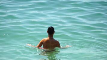 donna nuoto nel calma mare a tramonto, rallentatore, indietro Visualizza. concetto di corpo Immagine e fitness, godendo un' sereno spiaggia. contento donna con Perfetto in forma corpo gode mare spiaggia video