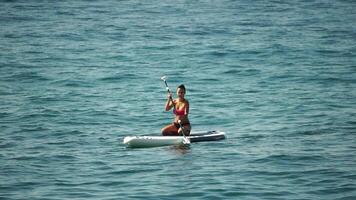 Man Sup Sea. Strong athletic man learns to paddle sup standing on board in open sea ocean on sunny day. Summer holiday vacation and travel concept. Aerial view. Slow motion video