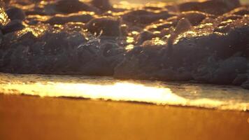 astratto mare onda, sfocato morbido schiumoso onde lavaggio d'oro sabbioso spiaggia su tramonto. oceano onde su sabbioso spiaggia. nessuno. vacanza ricreazione concetto. bokeh nautico estate oceano tramonto natura sfondo. video