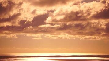 espaço de tempo fofo cumulus nuvens comovente dentro brilhante dourado pôr do sol céu sobre mar. abstrato aéreo natureza verão oceano pôr do sol, mar e céu visualizar. férias, viagem, feriado conceito. clima e clima mudança video