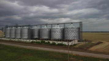 Grain elevator. Metal grain elevator in agricultural zone. Agriculture storage for harvest. Grain elevators on green nature background. Exterior of agricultural factory. Nobody. video