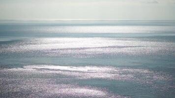 resumen aéreo mar verano Oceano puesta de sol naturaleza antecedentes. pequeño olas en calma agua superficie en movimiento difuminar con dorado bokeh luces desde Dom. día festivo, vacaciones y recreativo concepto. lento movimiento video