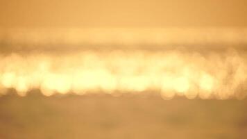 Blurred golden sea at sunset. The sun reflects and sparkles on the waves with bokeh, illuminating the golden sea. Holiday recreation concept. Abstract nautical summer ocean sunset nature background. video