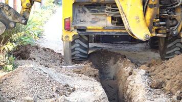 Excavator digs a trench to lay pipes. Close up of an excavator digging a deep trench. An excavator digs a trench in the countryside to lay a water pipe. video