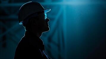 AI generated Silhouetted industrial worker wearing safety helmet and glasses against a blue background, evokes themes of engineering, safety, and professionalism in the workplace photo