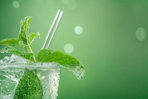 AI generated Close up image of a chilled mint julep glass with condensation droplets, mint sprigs, and a straw, set against a cool, green, gradient background with empty space for text photo