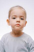 retrato de un pequeño grave triste niña en un gris antecedentes foto