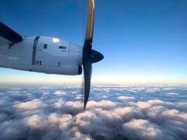 Spinning propeller of an airplane flying above the clouds in the blue sky photo