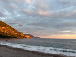 Mountain range in the rays of the setting sun on the seashore photo