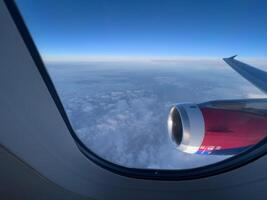 View from the window on the turbine and the wing of an airplane flying above the clouds photo