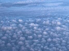 Airplane view of white cumulus clouds in sunbeams on blue sky photo