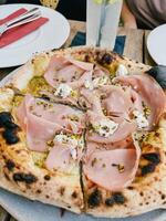 Mortadella pizza cut into several pieces stands on a table in a restaurant photo