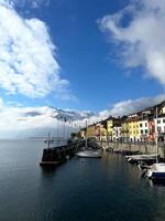Como, Italy - 12 november 2023. Boats are moored at the pier of the colorful town of Domaso. Como, Italy photo