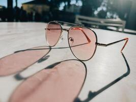 aviador estilo Gafas de sol emitir sombra en blanco mármol mesa foto