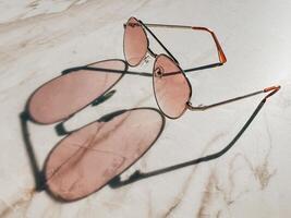 Brown sunglasses cast a colored shadow on a marble table top photo
