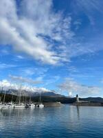 Yachts moored at the breakwater with a lighthouse at the foot of the mountains photo