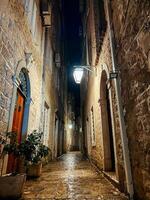 antiguo estrecho calle de un pequeño medieval pueblo iluminado por linternas foto