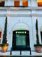 Tivat, Montenegro - 25 december 2022. Trees in tubs decorated with luminous garlands near the store window. Caption. Rolex photo