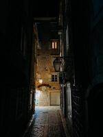 buda, montenegro - 25 diciembre 2022. estrecho calle de un antiguo pueblo con Roca edificios iluminado por linternas a noche foto