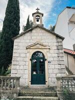 Dubrovnik, Croatia - 25 december 2022. Bell with a cross over an old stone chapel with a green wooden door photo